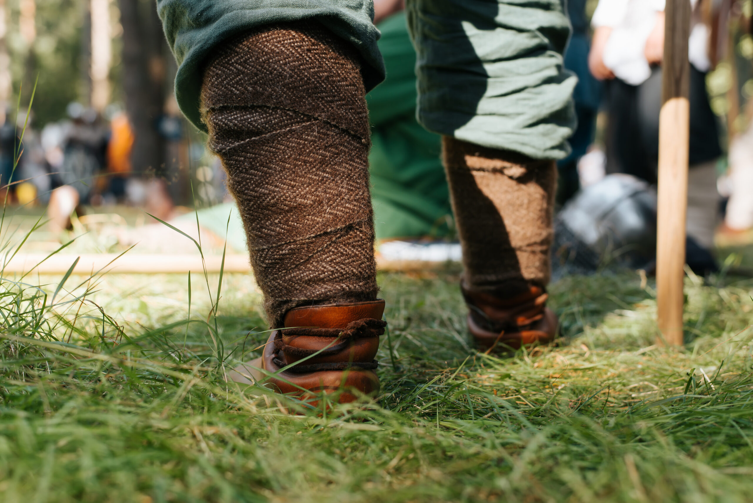 Nahaufnahme eines Wikingerbeins mit schützendem Zopf. Krieger steht im Freien auf einer Wiese, Ansicht aus der Froschperspektive.