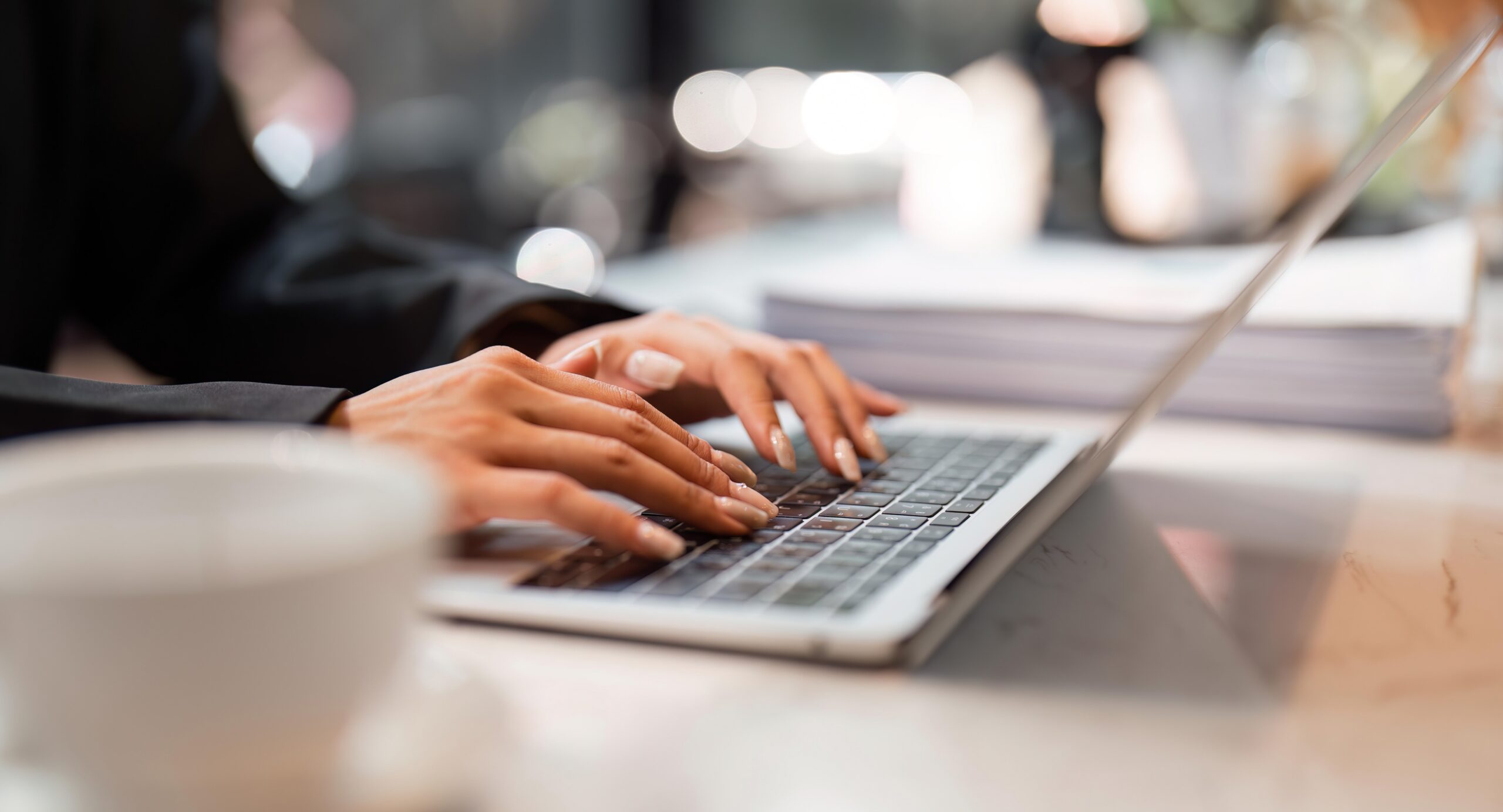 Closeup image of a business woman’s hands working and typing on laptop keyboard on table